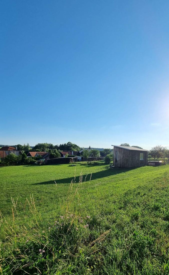 Louka a v dálce maringotka u kraje vesnice